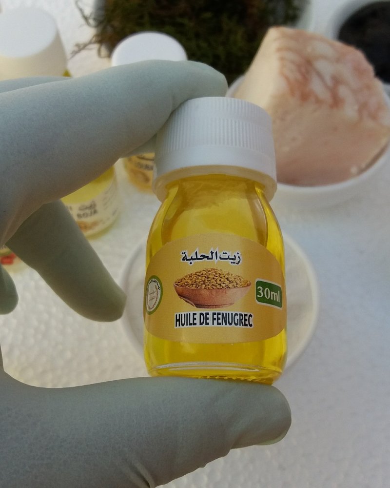 رجل مغربي يبتسم بثقة وخلفه زجاجة من زيت الحلبة، مما يعكس النتائج الإيجابية المتوقعة من استخدام اسرع علاج لتكبير الذكر بشكل طبيعي وآمن.