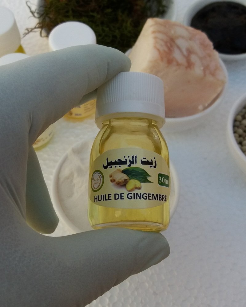 صورة حيوية لجذر الزنجبيل الطازج بجانب زجاجة من زيته، مما يسلط الضوء على خصائصه المحفزة للدورة الدموية والتي تجعله مكوناً مهماً في اسرع علاج لتكبير الذكر.